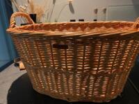 Robust flettet kurv i pileflet anvendt som brændekurv med praktiske hanke til transport af brænde.