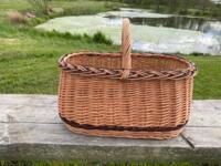 Stor kurv i flet fyldt med frugt, grønt og dagligvarer, robust og rummelig til indkøb.